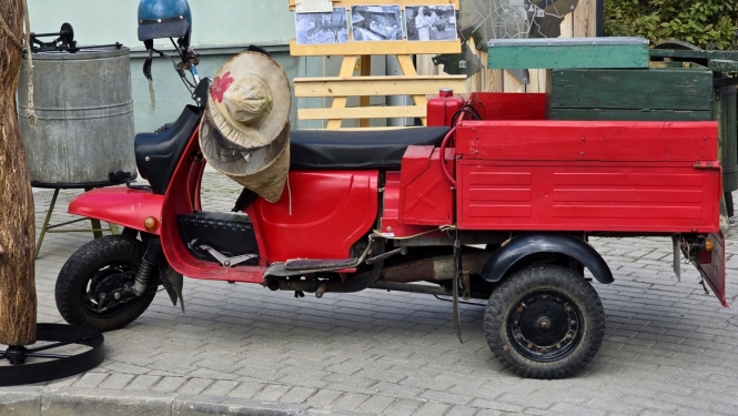 Sarkans motorollers ar kravas kasti pilsētvidē