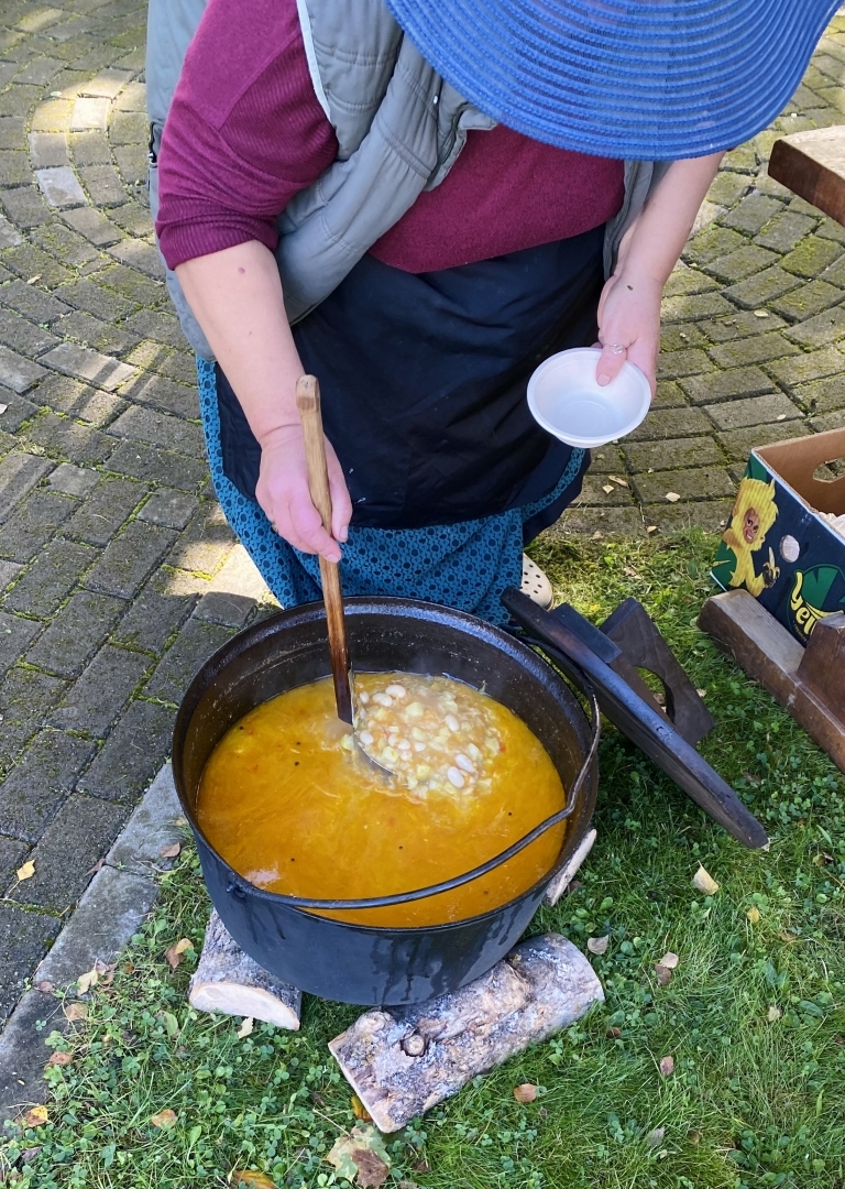 Latvijas Lauksaimniecības muzeja pagalmā sieviete vāra oranžu smeķīgu zupu